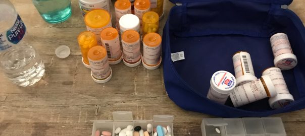 Table view of prescription medications in bottles and in a travel bag