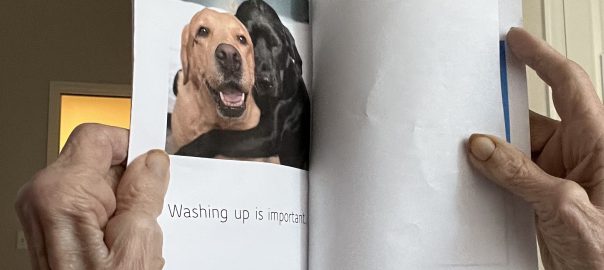 Hands of elderly person holding a booklet on Washing Up